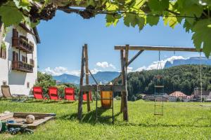 a playground in a field with chairs and a building at Sallrain Hof Apartment 1 in Collalbo +25 photos