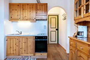 a kitchen with wooden cabinets and a black stove at Sallrain Hof Apartment 1 in Collalbo