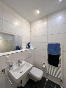 a white bathroom with a sink and a toilet at Große Terrassenwohnung mit Seeblick in Stechlin +22 photos
