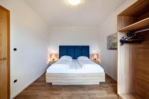 a bedroom with a large bed with a blue headboard at Gartenheim App Verena in Schenna