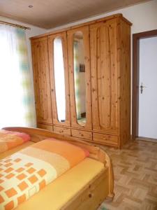 a bedroom with a bed and a wooden cabinet at Ferienwohnung Wassergartenparadies in Harsdorf +26 photos