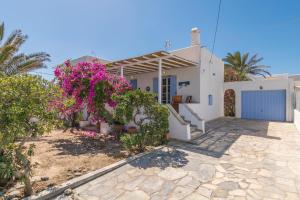 a white house with purple flowers in front of it at Alegria Villa in Pollonia