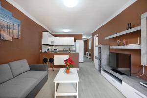 a living room with a couch and a tv and a kitchen at La Casita de Edu in Puerto de Santiago