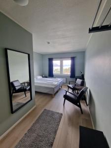 a bedroom with a bed and two chairs and a mirror at Lyngenfjord Hotel in Skibotn +18 photos