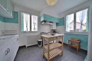 a kitchen with white and green walls and windows at Luchon Maison Flor in Luchon