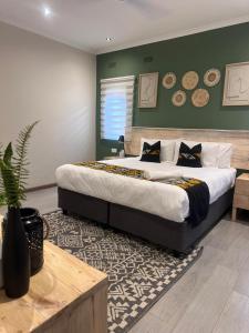 a bedroom with a large bed with green walls at Imbarudo Residence in Victoria Falls