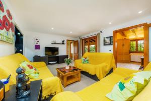 a living room with yellow couches and a tv at Can Magraner in Port de Pollensa