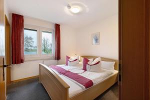 a bedroom with a bed with white and pink pillows at Ferienwohnungen Carstensen in Nordstrand