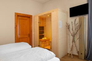 a bedroom with a bed and a cabinet with a television at Edelweiss Alp Rooms in Castello Tesino