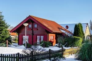 a red house with a fence in the snow at Emslandstube in Walchum