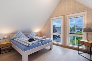 a bedroom with a bed with blue sheets and windows at Ferienhaus Wasserfall in Bestwig