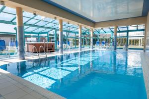 a swimming pool with blue water in a building at Royal Park Hotel & Spa in Mielno