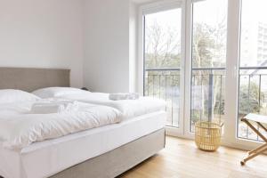 a white bedroom with a bed and a balcony at Steuerbord in Böhl