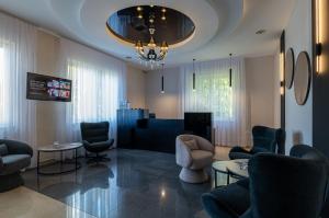 a living room with chairs and tables and a chandelier at Royal Park Hotel & Spa in Mielno