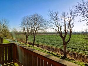 a balcony with a view of a field with trees at Ferienwohnungen Carstensen in Nordstrand