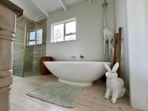a bathroom with a large white tub and a shower at The Blue Dragonfly in Jeffreys Bay