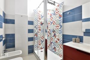 a bathroom with a shower with blue and white tiles at Appartamentino in Bari Sardo +10 photos