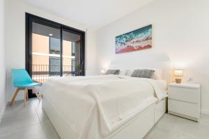 a white bedroom with a bed and a blue chair at Costa Dorada Perle in Calafell +18 photos