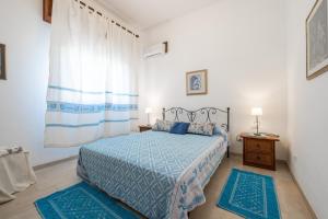a bedroom with a bed with blue comforter and blue rugs at Villa Rita in Flumini di Quartu