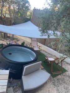 a backyard with a hot tub and a hammock and chairs at La Tiny House des Oliviers et son jacuzzi in Mouriès
