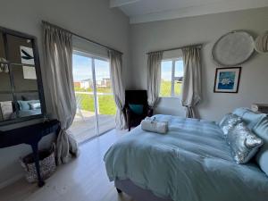 a bedroom with a bed and a large window at The Blue Dragonfly in Jeffreys Bay