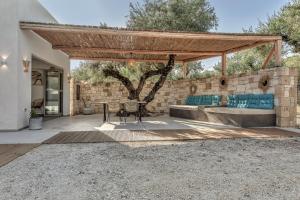 a patio with a table and a stone wall at Natura Oliva House in Alikanas