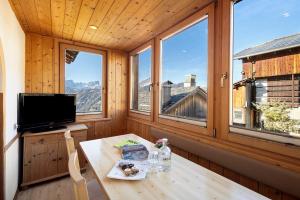 ein Zimmer mit einem Tisch, einem Fernseher und Fenstern in der Unterkunft Ciablun in Wengen