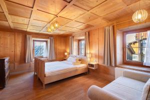 ein Schlafzimmer mit einem Bett, einer Couch und zwei Fenstern in der Unterkunft Ciablun in Wengen