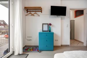 a living room with a blue dresser and a tv at Tinas Ferienwohnung in Hergensweiler