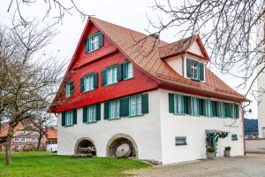 a red and white house with a red roof at Tinas Ferienwohnung in Hergensweiler