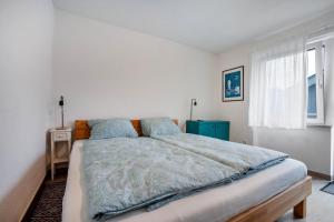a white bedroom with a large bed with blue pillows at Tinas Ferienwohnung in Hergensweiler