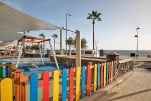 a colorful fence next to the beach with a swing at Apartamento Avenida Marítima in Candelaria