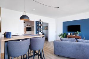 a kitchen and living room with a bar with blue chairs at Ferienwohnung Clara in Bremerhaven