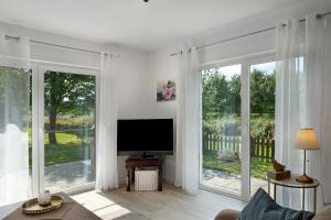 a living room with large windows and a flat screen tv at Ferienhaus Apfelzauber in Twielenfleth