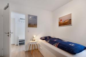 a white bedroom with a bed and a table at Ferienhaus Apfelzauber in Twielenfleth