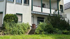 a building with a balcony and stairs in the grass at Villa Fichteneck in Oberhof