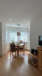 a living room with a table and chairs and a television at Villa Fichteneck in Oberhof