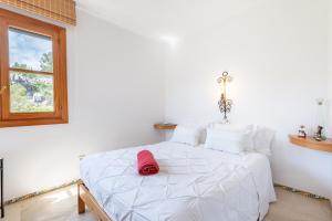 a bedroom with a white bed with a red hat on it at Montemar 36 in Port de Soller +18 photos