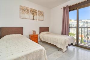 a bedroom with two beds and a large window at Argali Beach Almuñecar in Almuñécar
