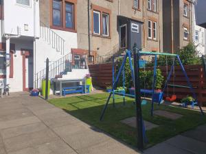 a playground with a swing set in a yard at Saphire Apartments Spacious 1 Bed Apartment Sleeps 6 with Free Parking and Garden in Giffnock