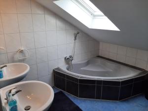 a bathroom with a tub and a sink at Fewo beim Schmied Straßkirchen in Vogtareuth +19 photos