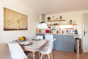 a kitchen with a table and white chairs in a room at Logement de charme les Araucarias in La Garde