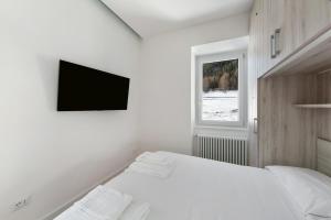 a white bedroom with a bed and a tv on the wall at Dolomiti e Misurina My dreams in Misurina