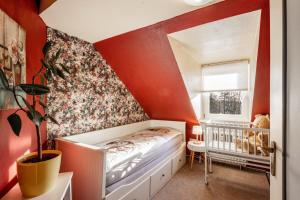 a childs bedroom with red walls and a crib at Das Spatzennest in Bad Sachsa