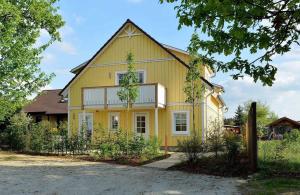 a yellow house with a fence in front of it at Ferienwohnung Hafen in Neuendorf am See