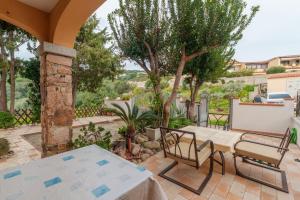 a patio with a table and chairs and trees at Villa Marisol Agrustos in Budoni