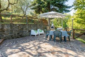 a patio with a table and chairs and an umbrella at Il Colletto Romantic Stonehouse in Pescia +15 photos