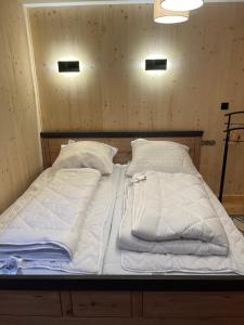a bed with white sheets and pillows on it at Urige idyllische Hütte mit Sauna in Grainet