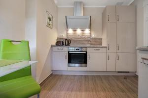 eine Küche mit weißen Schränken und einem grünen Stuhl in der Unterkunft Ferienwohnung Bleichen in Stralsund
