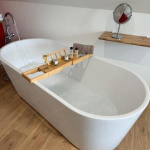 a white bath tub in a bathroom with a mirror at Aux Charmes - Suites Prestige et Petit Déjeuner en chambre - Cote d Opale in Isques +21 photos